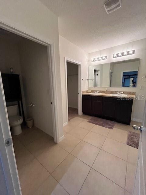 bathroom with tile patterned floors, toilet, vanity, and a textured ceiling