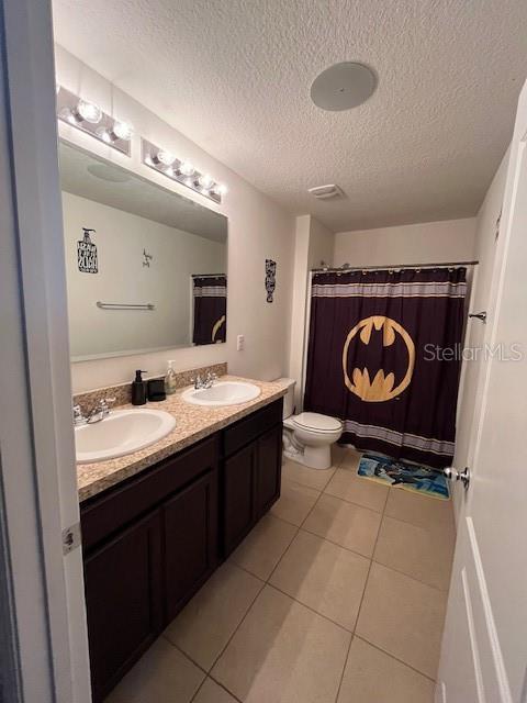 bathroom with vanity, a textured ceiling, tile patterned floors, toilet, and walk in shower