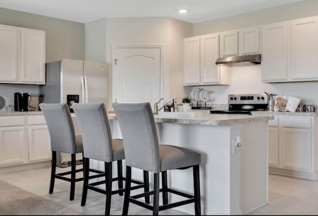 kitchen with white cabinetry, appliances with stainless steel finishes, a breakfast bar area, and a center island with sink