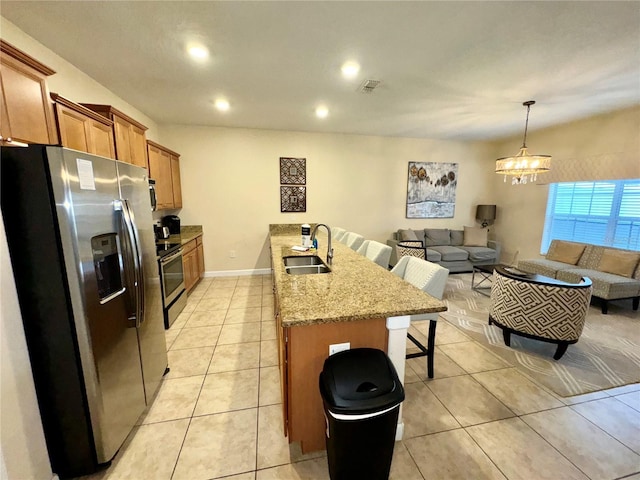 kitchen featuring sink, light stone counters, decorative light fixtures, a kitchen breakfast bar, and stainless steel appliances