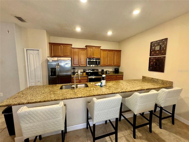 kitchen with sink, a breakfast bar, kitchen peninsula, and appliances with stainless steel finishes