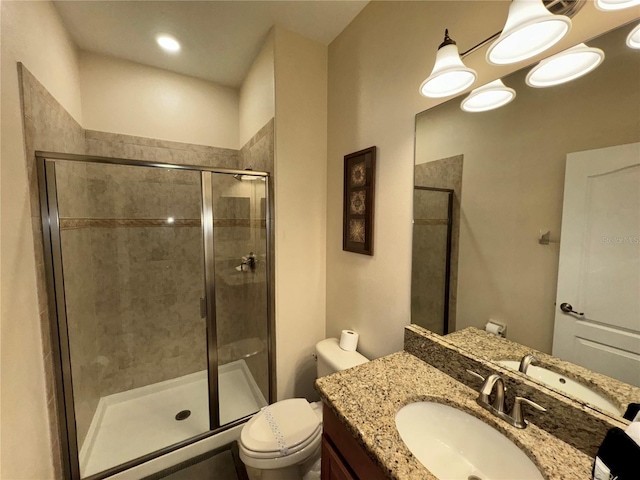 bathroom featuring a shower with door, vanity, and toilet