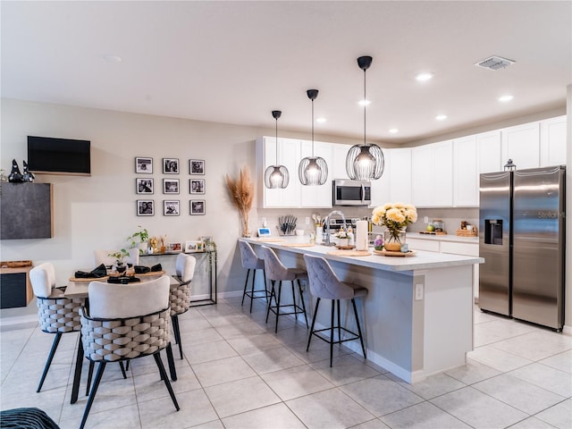 kitchen with hanging light fixtures, a kitchen breakfast bar, white cabinets, and appliances with stainless steel finishes