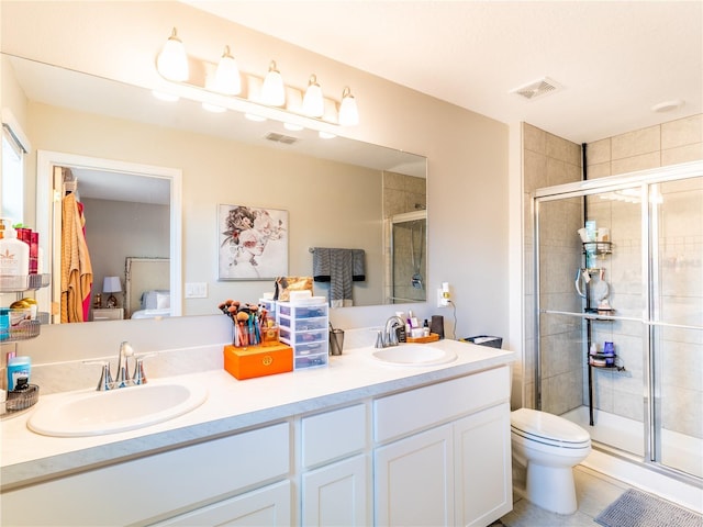 bathroom with a shower with door, vanity, tile patterned floors, and toilet