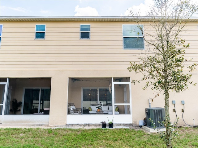 back of property featuring a lawn, a sunroom, and central air condition unit