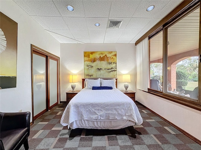 bedroom featuring dark carpet, a paneled ceiling, and a closet