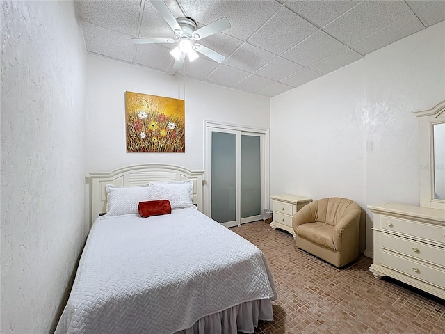 bedroom featuring a paneled ceiling, a closet, and ceiling fan