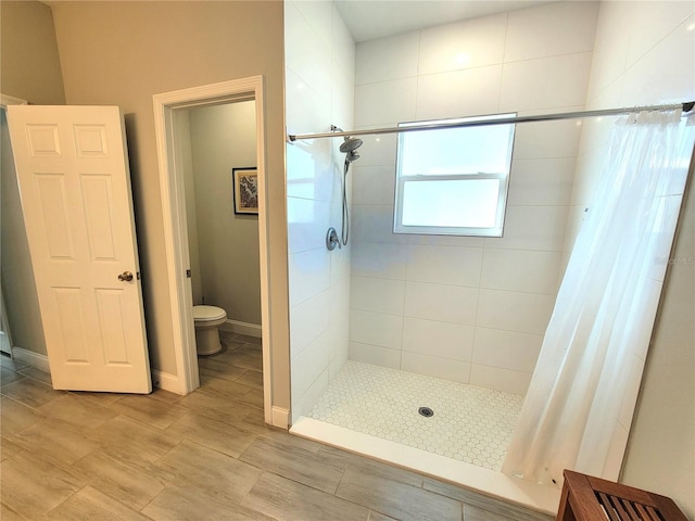 bathroom featuring curtained shower, wood-type flooring, and toilet