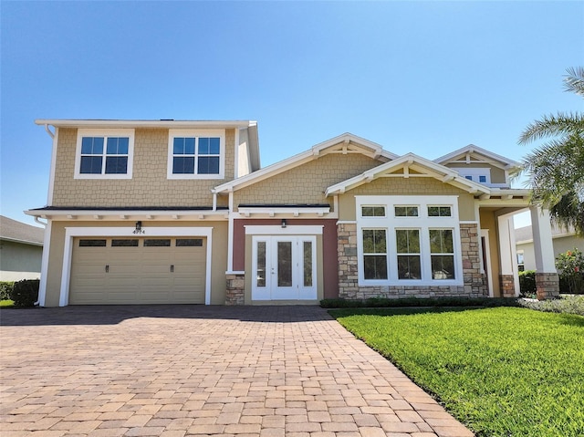 craftsman-style home featuring stone siding, decorative driveway, french doors, a front lawn, and stucco siding