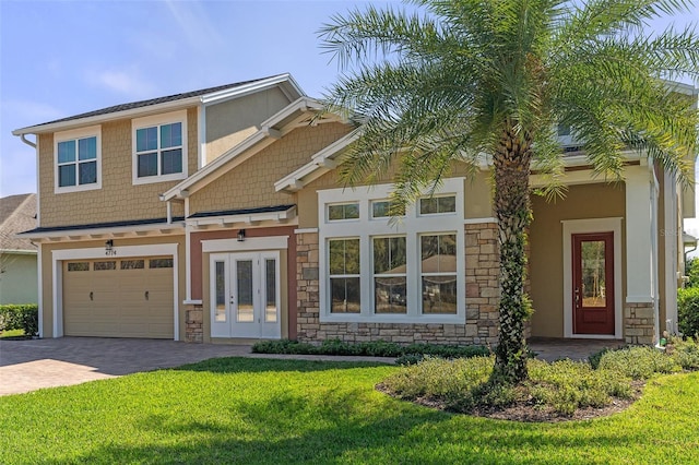 view of front facade featuring stone siding, an attached garage, decorative driveway, french doors, and a front lawn