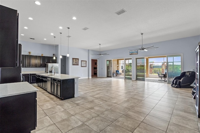 kitchen with light tile patterned floors, visible vents, open floor plan, and a sink