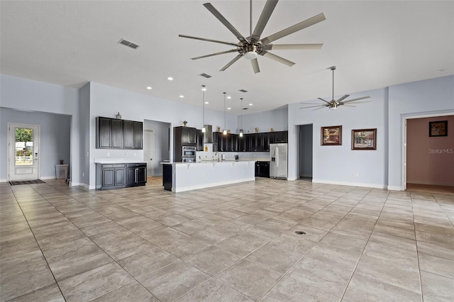 unfurnished living room with visible vents, a high ceiling, a ceiling fan, light tile patterned flooring, and baseboards