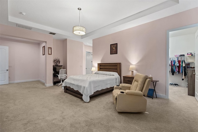 bedroom with a raised ceiling, light carpet, visible vents, and baseboards