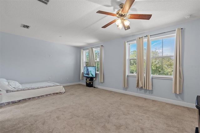 carpeted bedroom with a textured ceiling, ceiling fan, visible vents, and baseboards