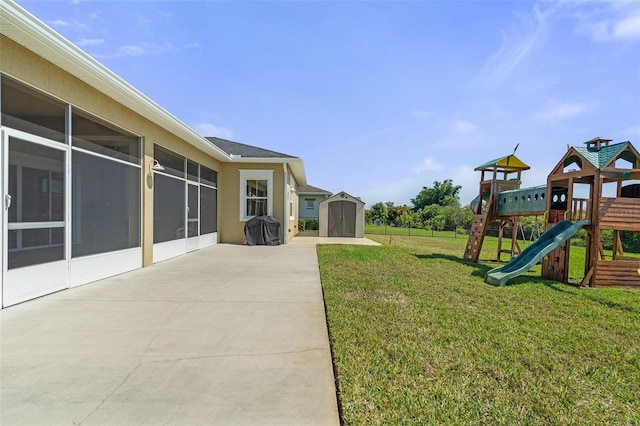 view of yard featuring a storage shed, a patio, a sunroom, an outbuilding, and a playground