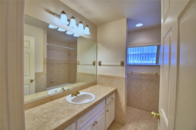 bathroom featuring tile patterned flooring, vanity, a shower, and tile walls