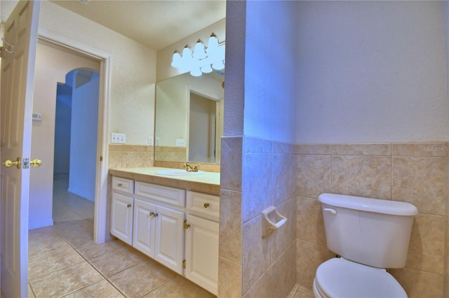 bathroom featuring tile patterned flooring, vanity, tile walls, and toilet