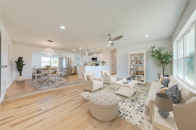 living room with ceiling fan and light wood-type flooring