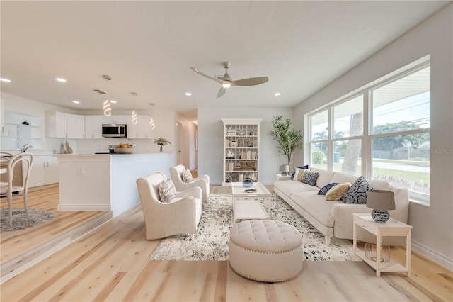 living room with light hardwood / wood-style flooring and ceiling fan