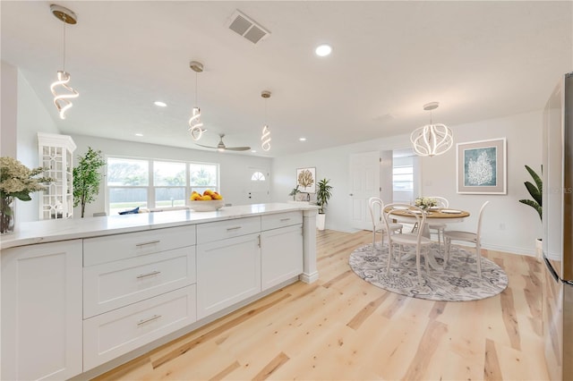 kitchen with a healthy amount of sunlight, decorative light fixtures, white cabinets, and light wood-type flooring