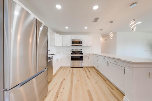 kitchen featuring pendant lighting, white cabinetry, kitchen peninsula, stainless steel appliances, and light hardwood / wood-style flooring