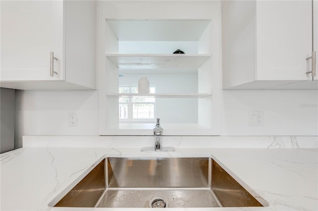 details with white cabinetry, sink, and light stone counters