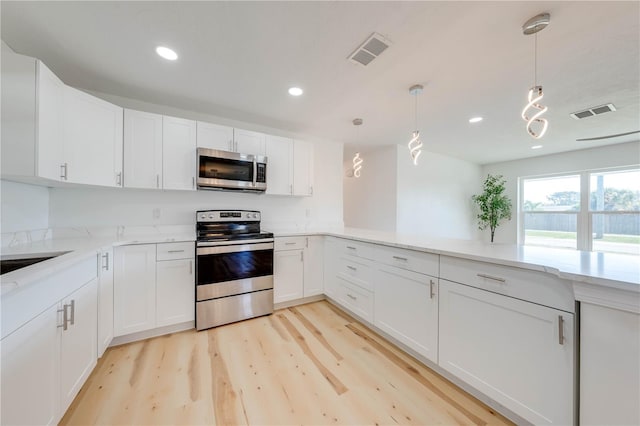 kitchen with white cabinetry, appliances with stainless steel finishes, and decorative light fixtures