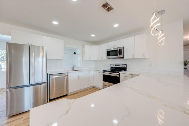 kitchen featuring white cabinetry, stainless steel appliances, light stone counters, and hanging light fixtures