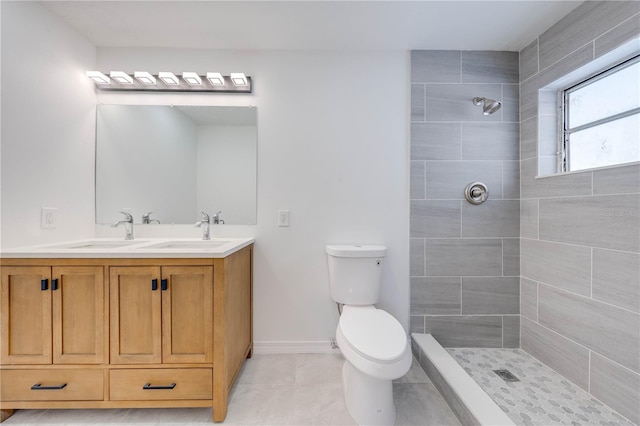 bathroom featuring vanity, toilet, tile patterned flooring, and a tile shower