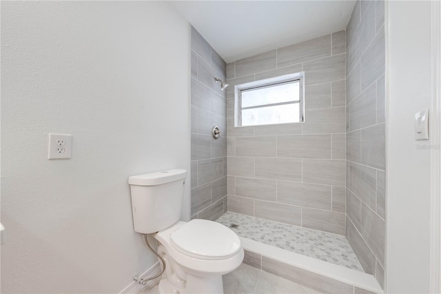 bathroom featuring a tile shower and toilet