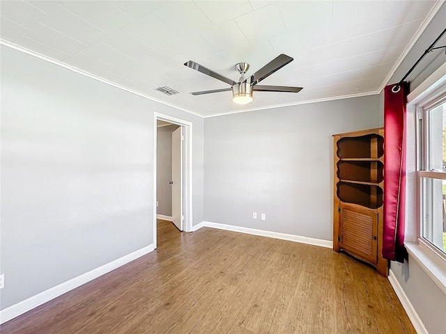 unfurnished room featuring baseboards, visible vents, a ceiling fan, wood finished floors, and crown molding