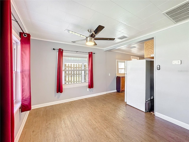 spare room featuring crown molding, visible vents, ceiling fan, and wood finished floors