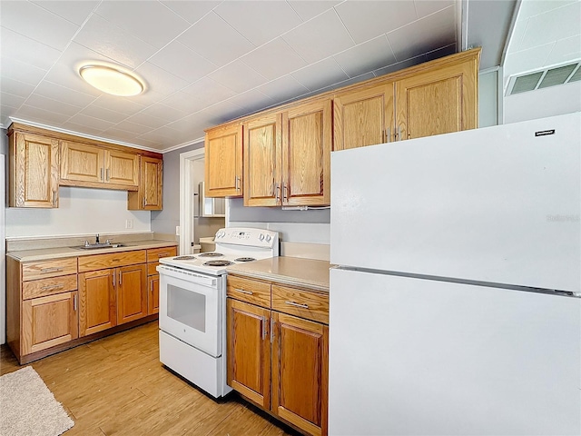 kitchen featuring white appliances, a sink, visible vents, light countertops, and light wood finished floors