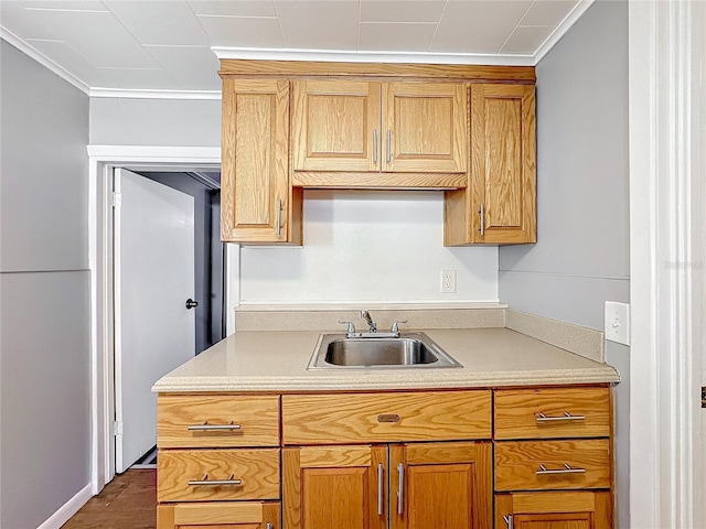 kitchen with light countertops, brown cabinetry, a sink, and crown molding