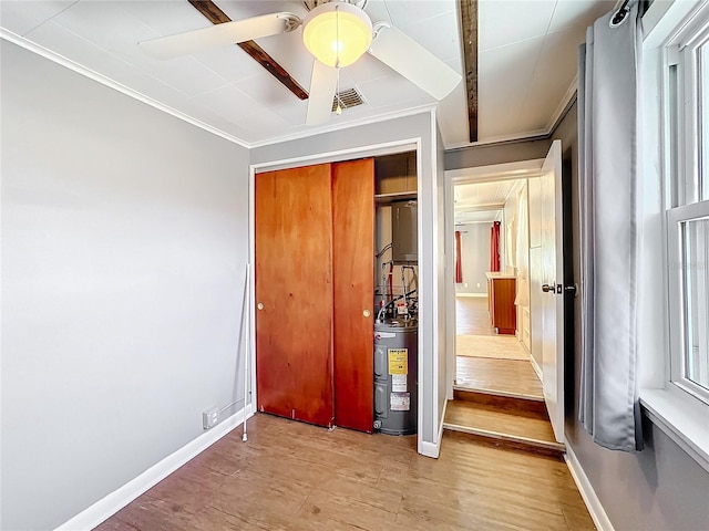 unfurnished bedroom with baseboards, visible vents, ceiling fan, wood finished floors, and electric water heater