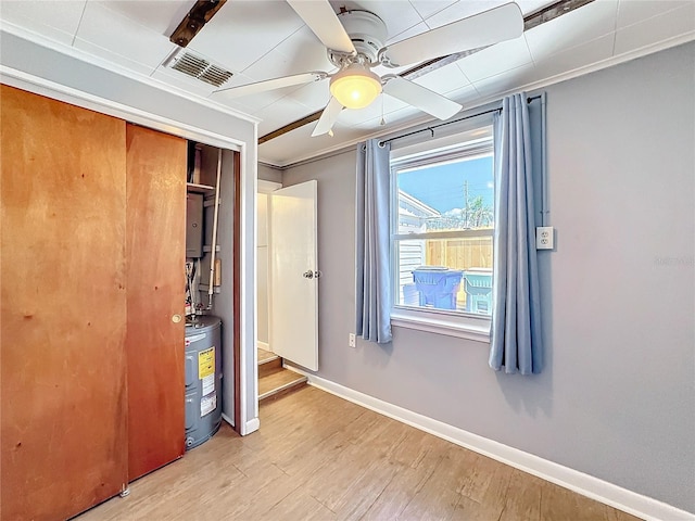 unfurnished bedroom with a closet, visible vents, electric water heater, wood finished floors, and baseboards