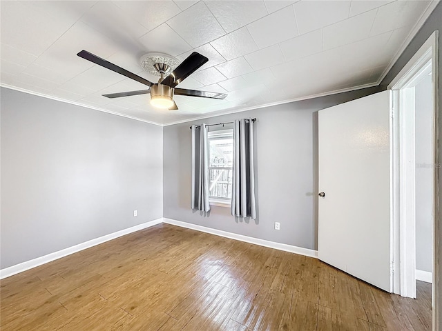 spare room with baseboards, crown molding, a ceiling fan, and wood finished floors