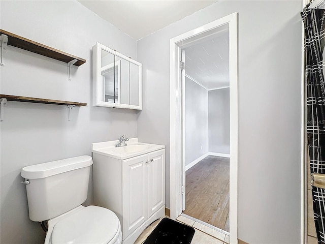 bathroom with toilet, tile patterned flooring, baseboards, and vanity