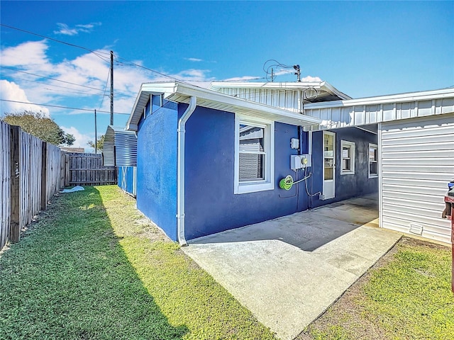 view of side of property featuring a patio, a lawn, a fenced backyard, and stucco siding