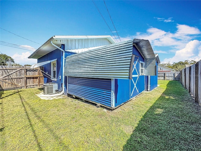 view of home's exterior with an outbuilding, central AC, a lawn, and a fenced backyard