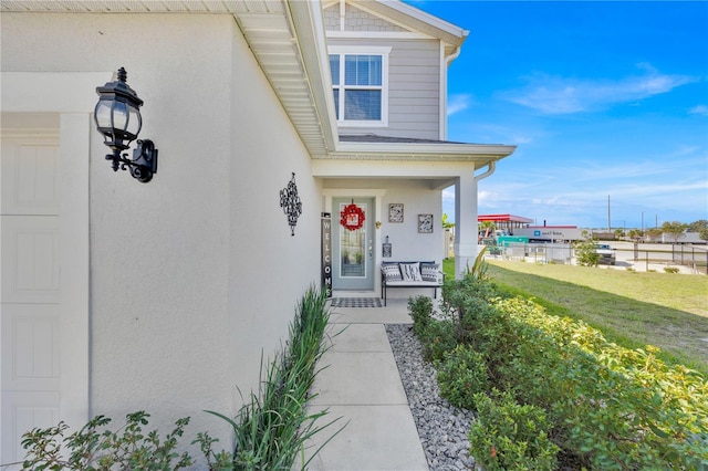 doorway to property with a yard and covered porch