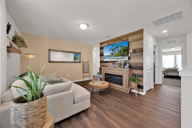 living room with dark hardwood / wood-style flooring, a textured ceiling, and wood walls