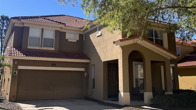 mediterranean / spanish house with a tiled roof, an attached garage, and stucco siding