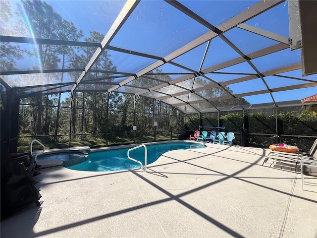 view of pool with a lanai, a pool with connected hot tub, and a patio