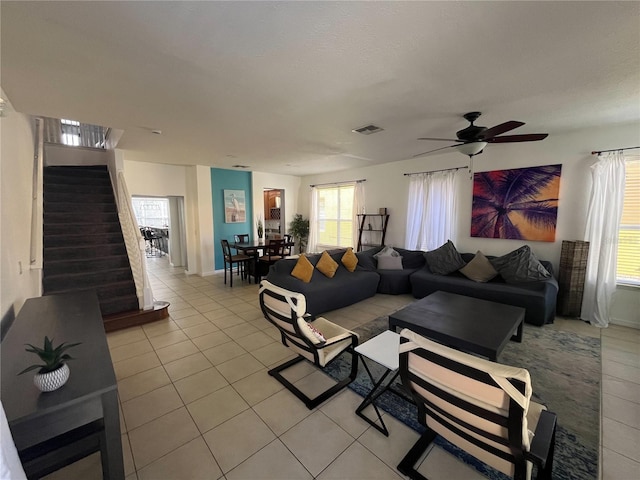 living area featuring visible vents, ceiling fan, stairway, and light tile patterned floors