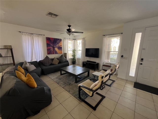 living room with a ceiling fan, visible vents, and light tile patterned floors