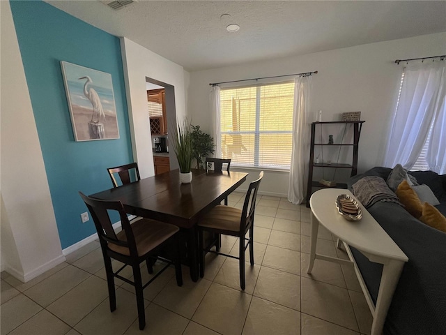 dining area with light tile patterned floors, a textured ceiling, visible vents, and baseboards