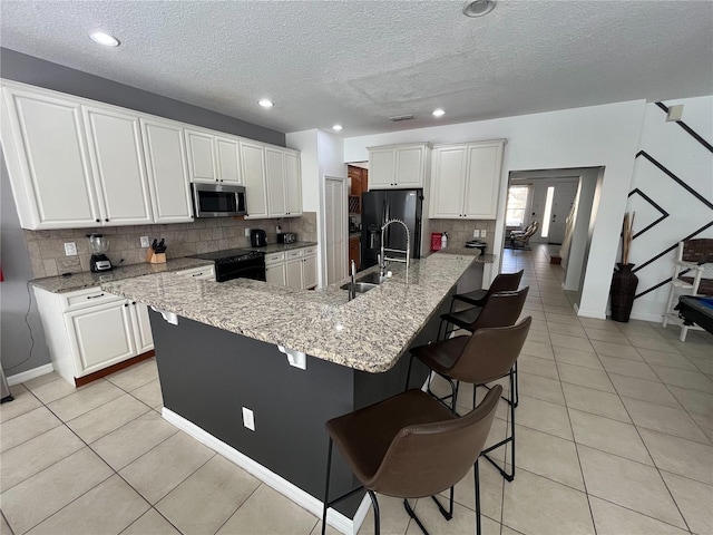 kitchen featuring black appliances, light tile patterned floors, and white cabinets