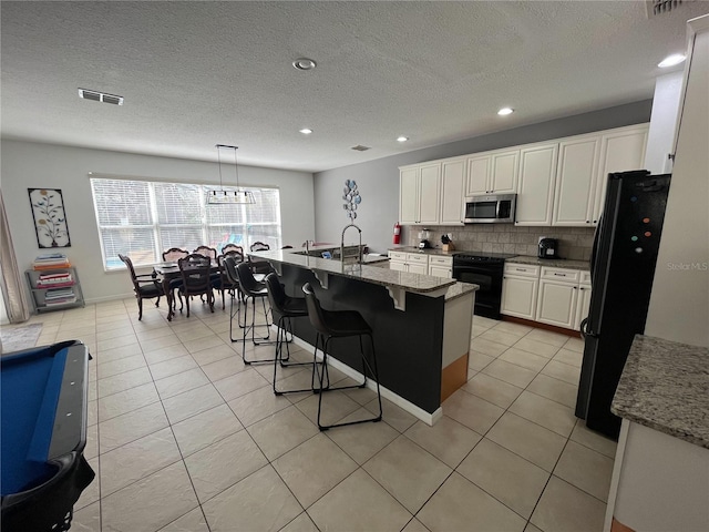 kitchen featuring black appliances, light tile patterned flooring, backsplash, and visible vents