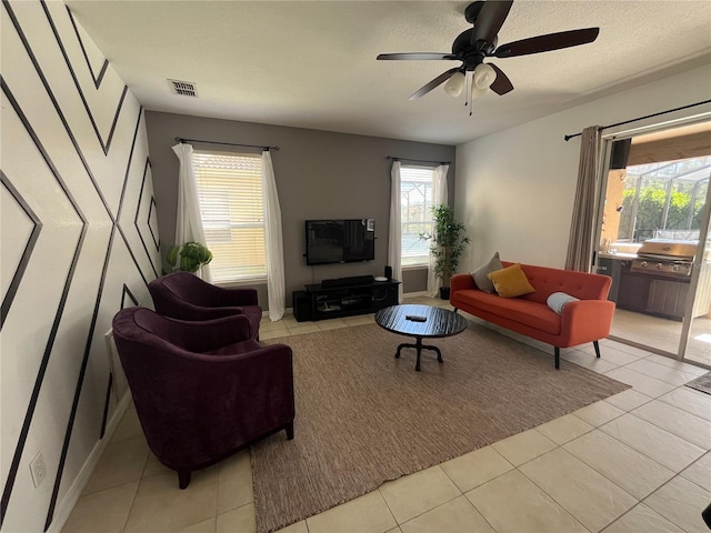 living room featuring a ceiling fan, visible vents, a textured ceiling, and light tile patterned floors